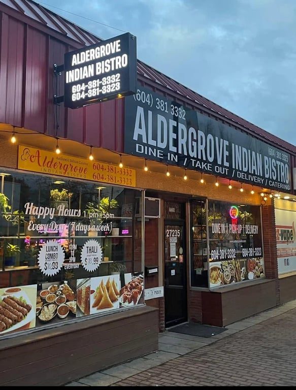 The Aldergrove Indian Bistro storefront on Fraser Highway: a dark red building with the bistro's big sign and photo-covered front windows