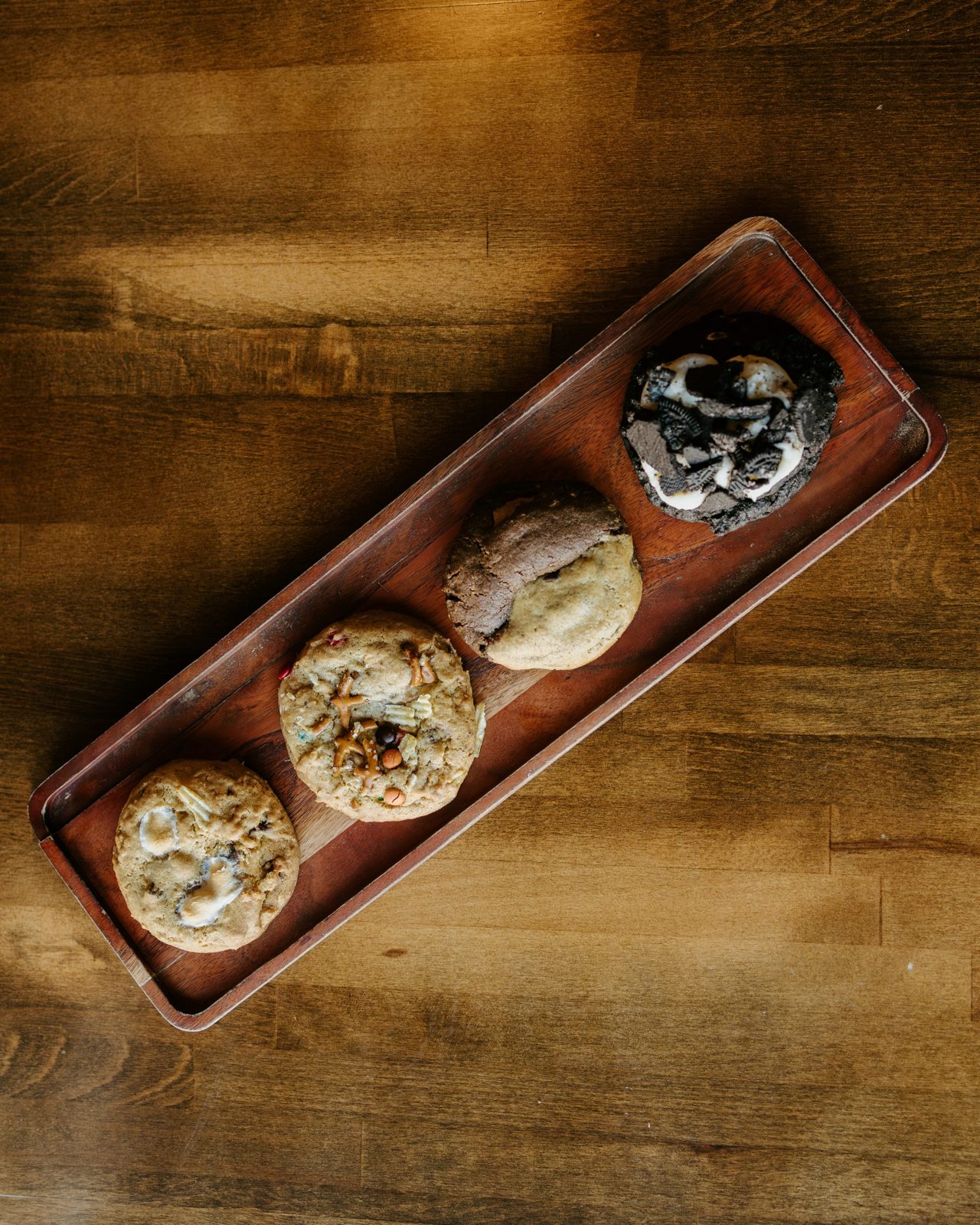 Four of ARCHR's big loaded cookies on a wooden tray, seen from above