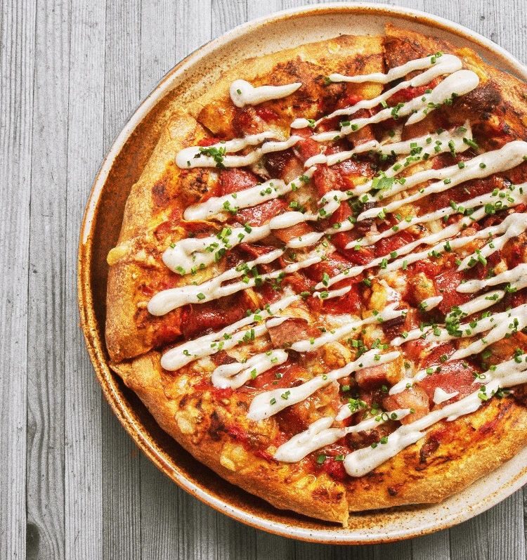 A thin-crust pizza with a drizzle of creamy sauce at The Barley Merchant