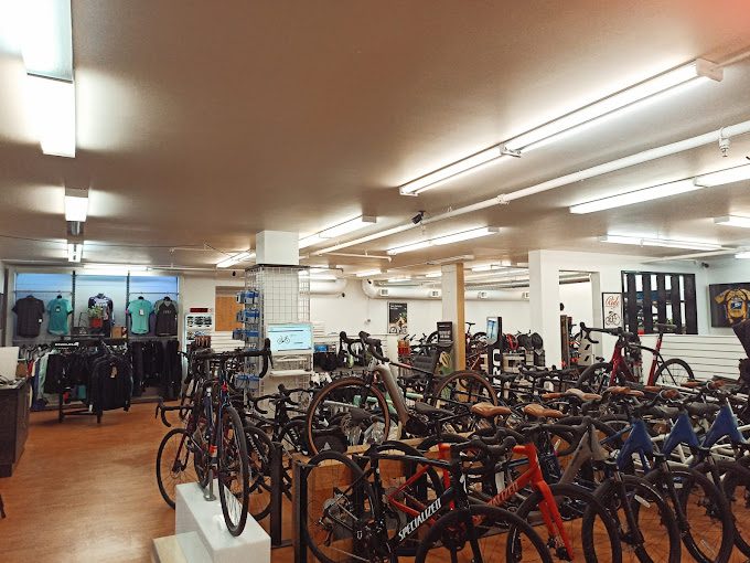 Inside Bicycle Sports Pacific's Langley shop: rows of road and mountain bikes on a wood floor, with cycling clothing along the back wall