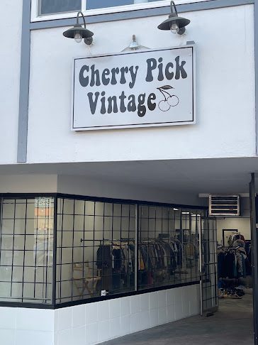 Cherry Pick Vintage's sign with a cherry logo above its black-framed shop windows on Fraser Highway in downtown Langley