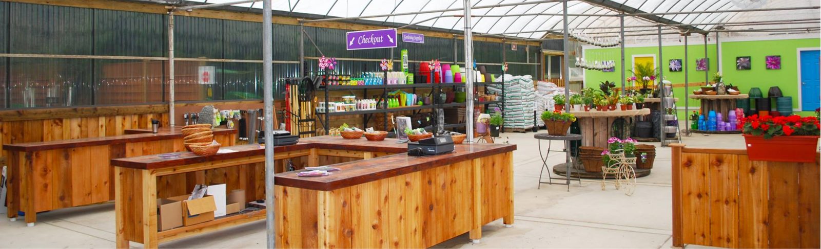 Clearview's wooden checkout counters under the greenhouse roof, with pots, garden products and a Checkout sign