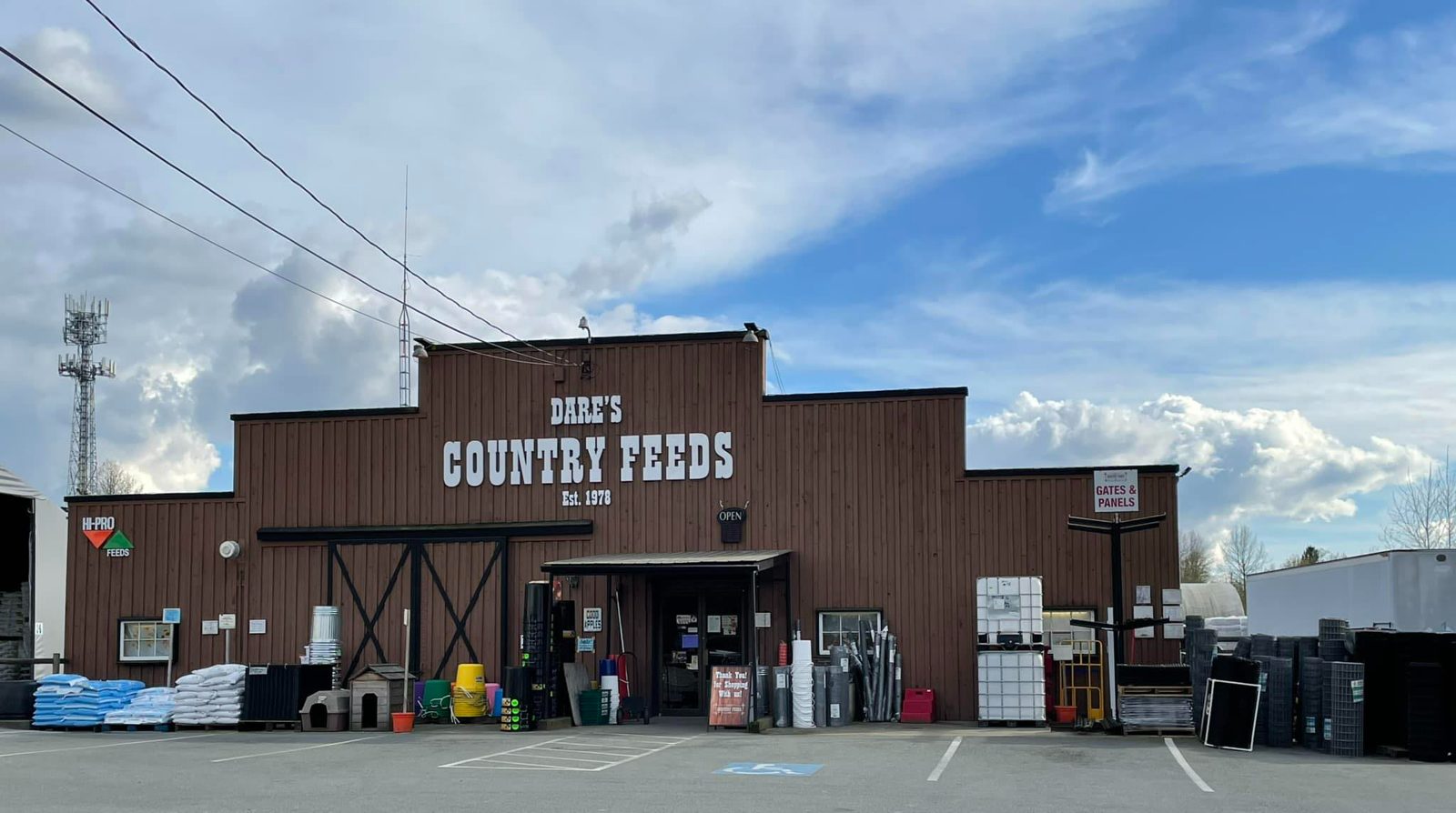 The brown, barn-style Dare's Country Feeds storefront on Fraser Highway, with bagged feed and supplies stacked outside