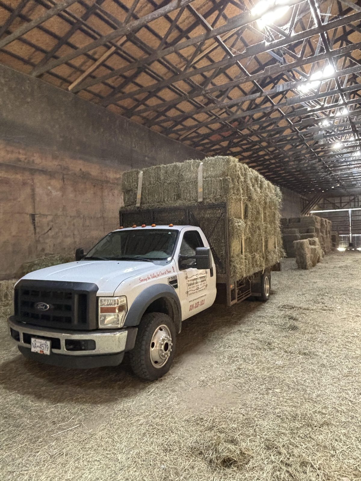 A Dare's Country Feeds pickup loaded with hay bales inside a hay storage barn