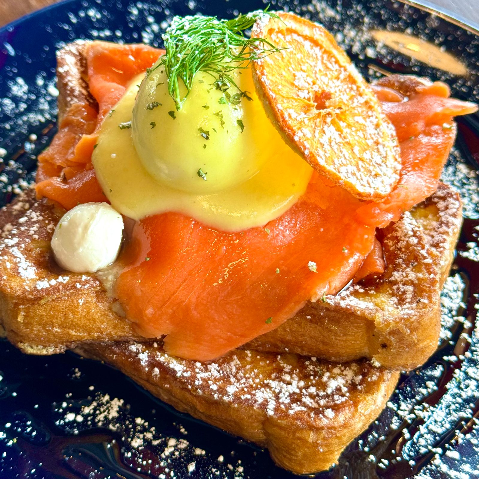 Egg Bomb's French toast stacked with smoked salmon, a poached egg in hollandaise and a dried orange slice