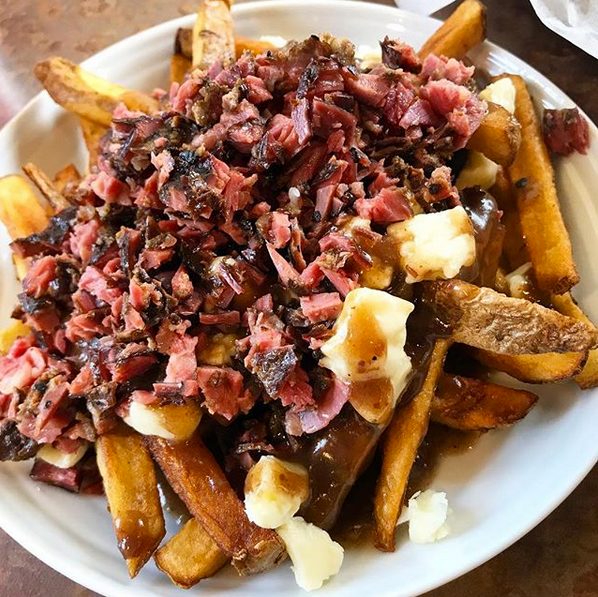 A plate of fries topped with gravy, cheese curds and chopped smoked meat