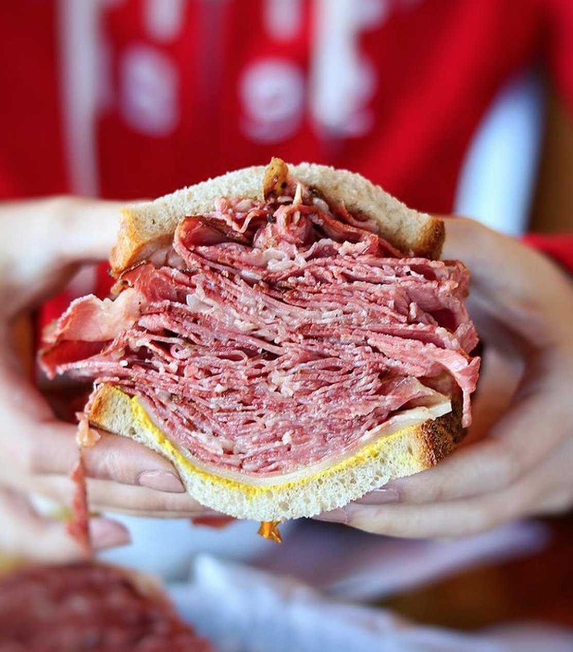 A thick-cut smoked meat sandwich on rye held up to show the stack