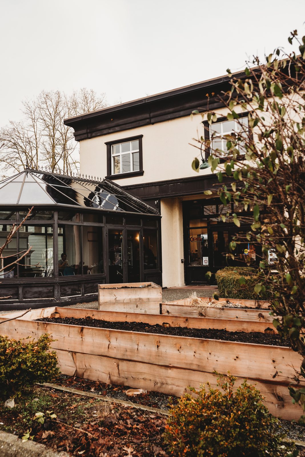 The Firehouse Cafe in Aldergrove: the cream-coloured former fire hall with a glass solarium entrance and raised garden beds out front