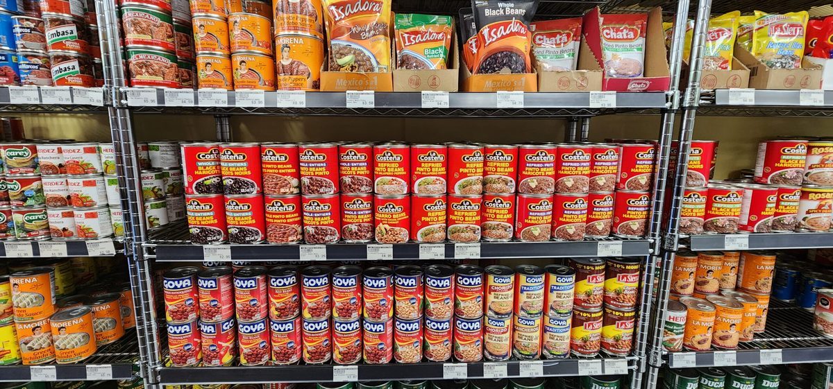 Shelves stacked with cans and jars of Latin American pantry goods at Los Guerreros