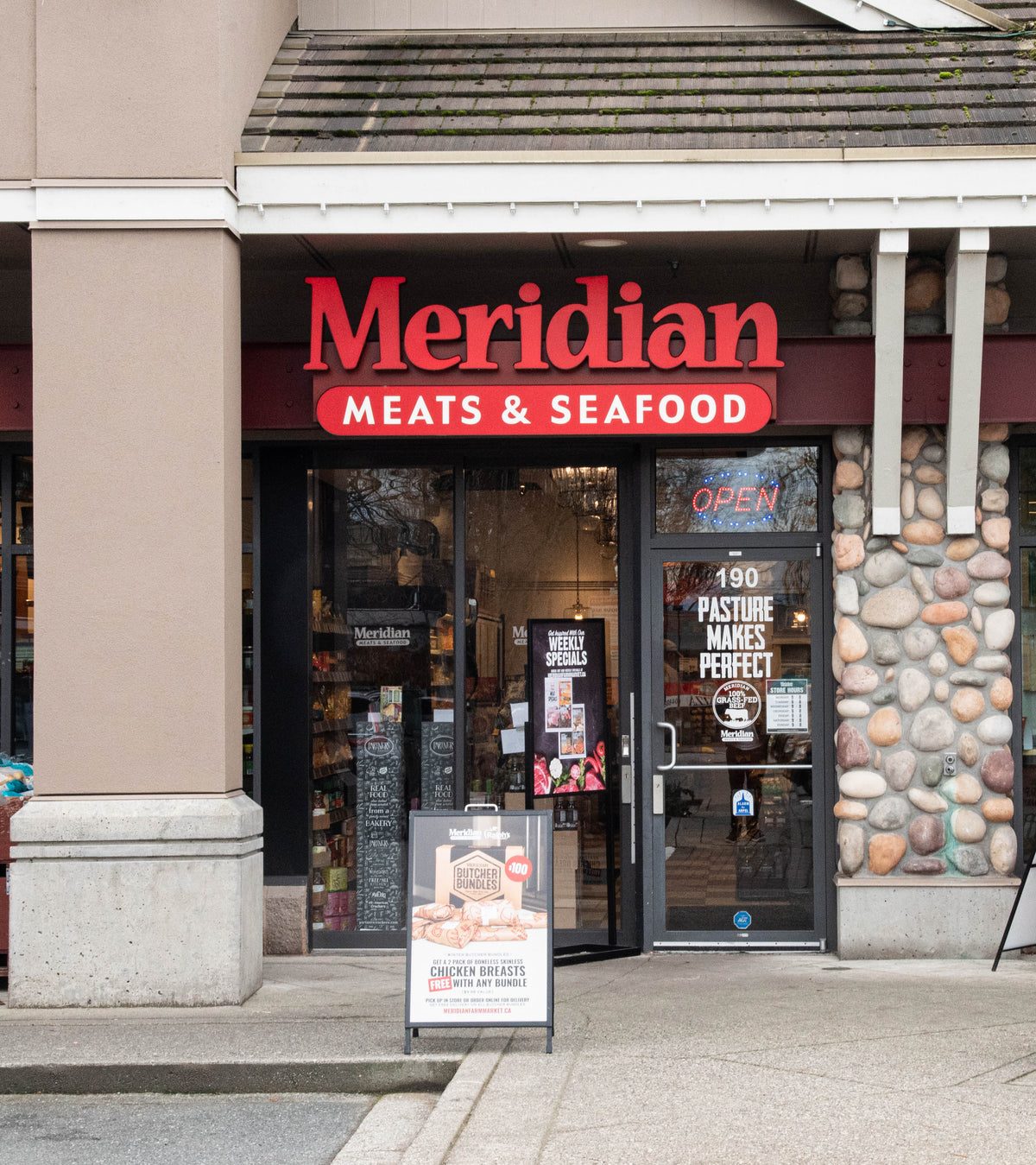 The Meridian Meats & Seafood storefront in Walnut Grove: a red sign over glass doors at unit 190, with a sandwich board out front