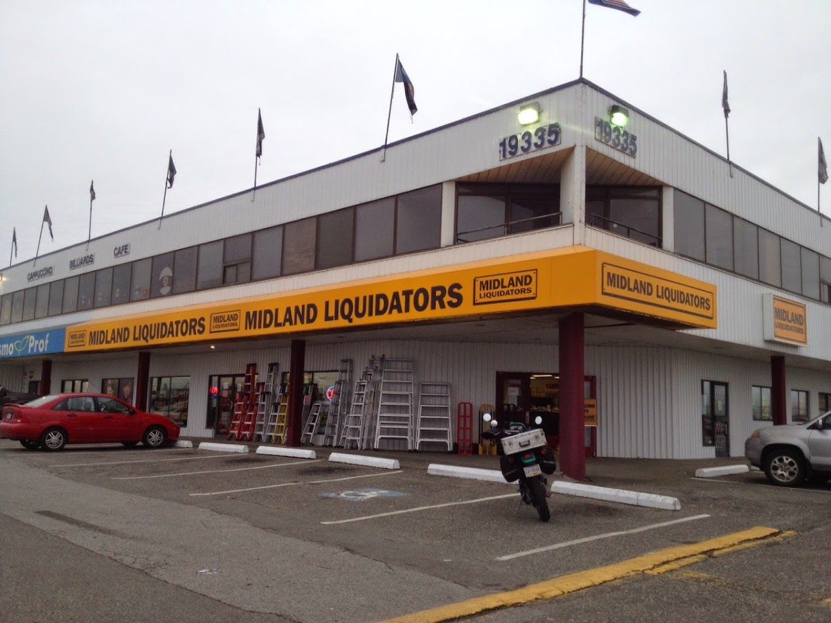 Midland Liquidators' long yellow sign across the front of the two-storey building at 19335 Langley Bypass
