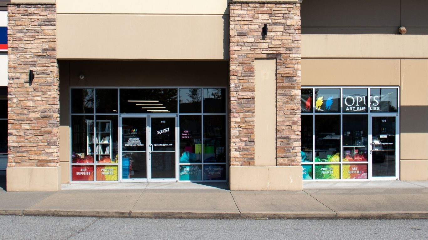 The Opus Art Supplies storefront in a stone-pillared plaza on Willowbrook Drive, its windows lined with colourful art supply posters