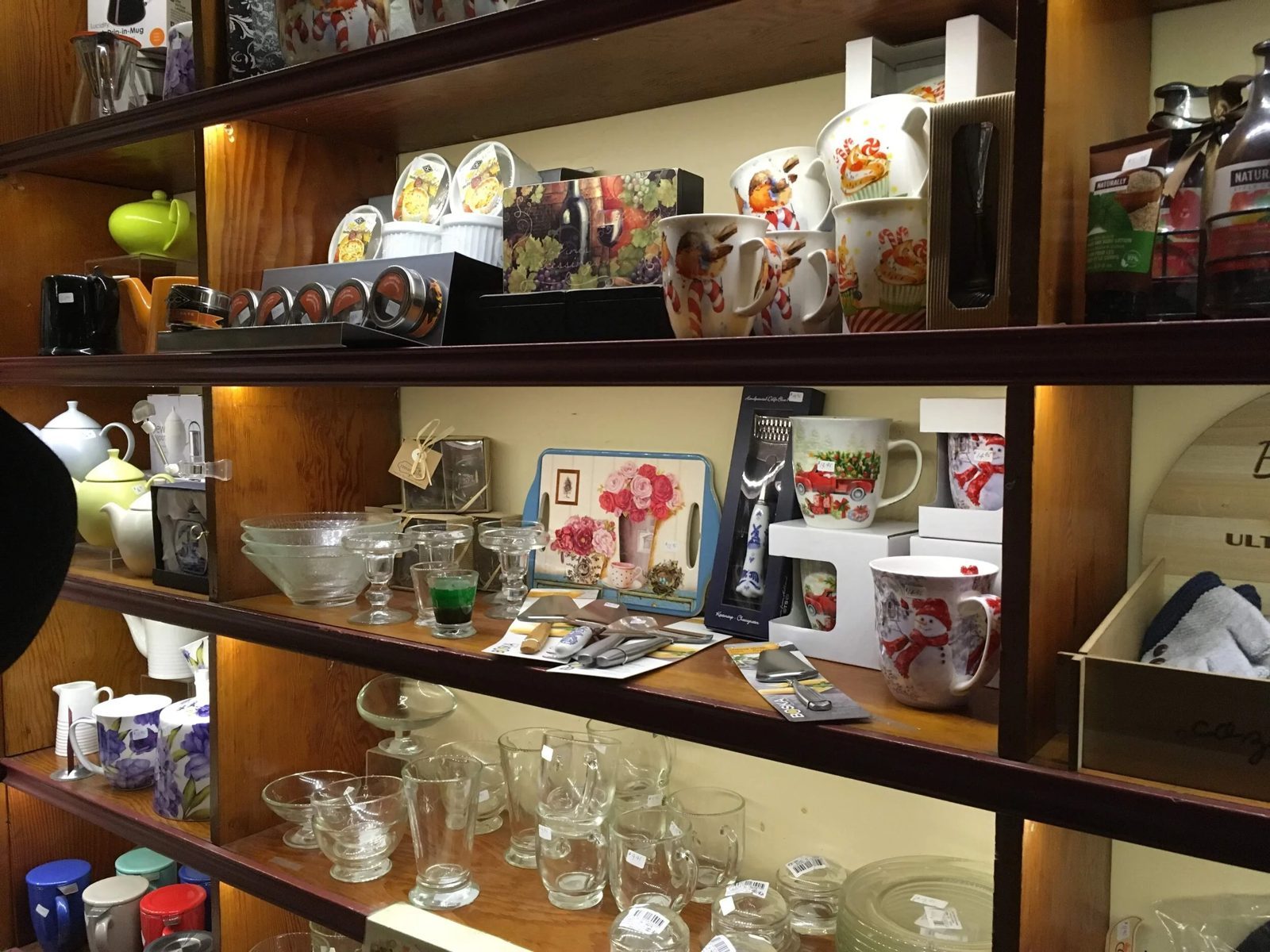 Dark wooden shelves inside Porters Bistro lined with teapots, floral mugs and glassware for sale