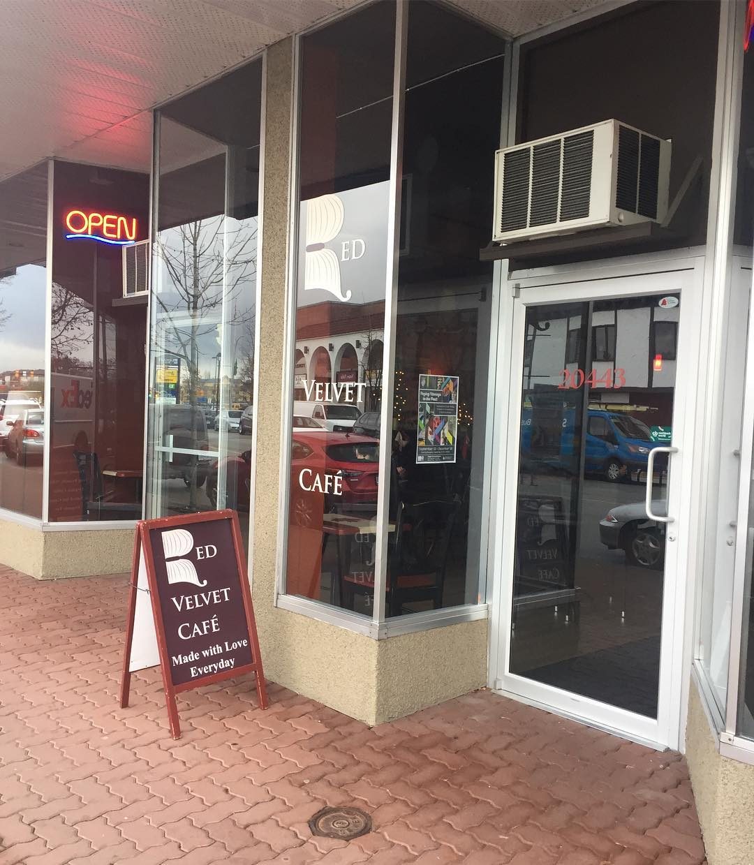 Red Velvet Café's glass storefront on Douglas Crescent, with an Open sign in the window and a sandwich board reading Made with Love Everyday on the brick sidewalk