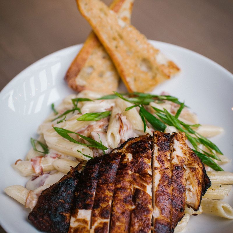 Blackened four cheese penne topped with sliced blackened chicken and garlic toast