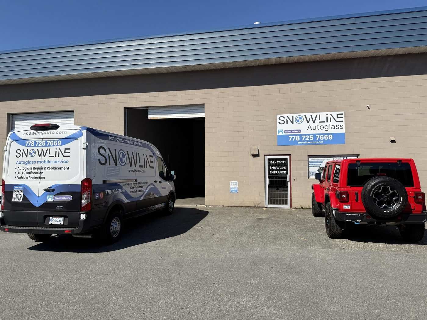 Snowline Autoglass's unit on the Langley Bypass: a beige block building with a branded mobile-service van parked outside, a Snowline sign above the entrance door and a red Jeep parked to the right