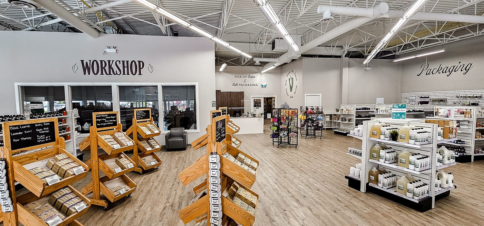 Inside Voyageur's retail store: wooden crates of soap ingredients, white shelving of bottles and a Workshop room with windows at the back