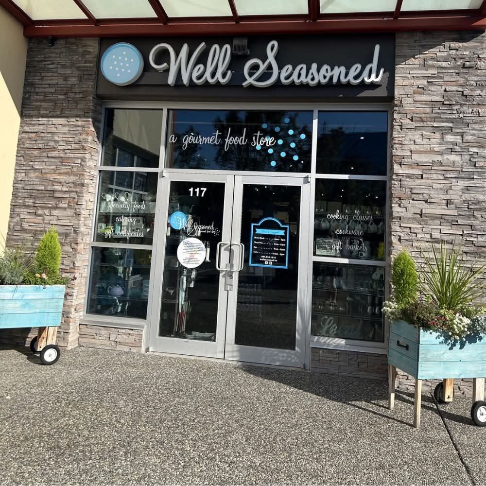 The Well Seasoned shopfront, glass doors under a grey stone facade with planters out front