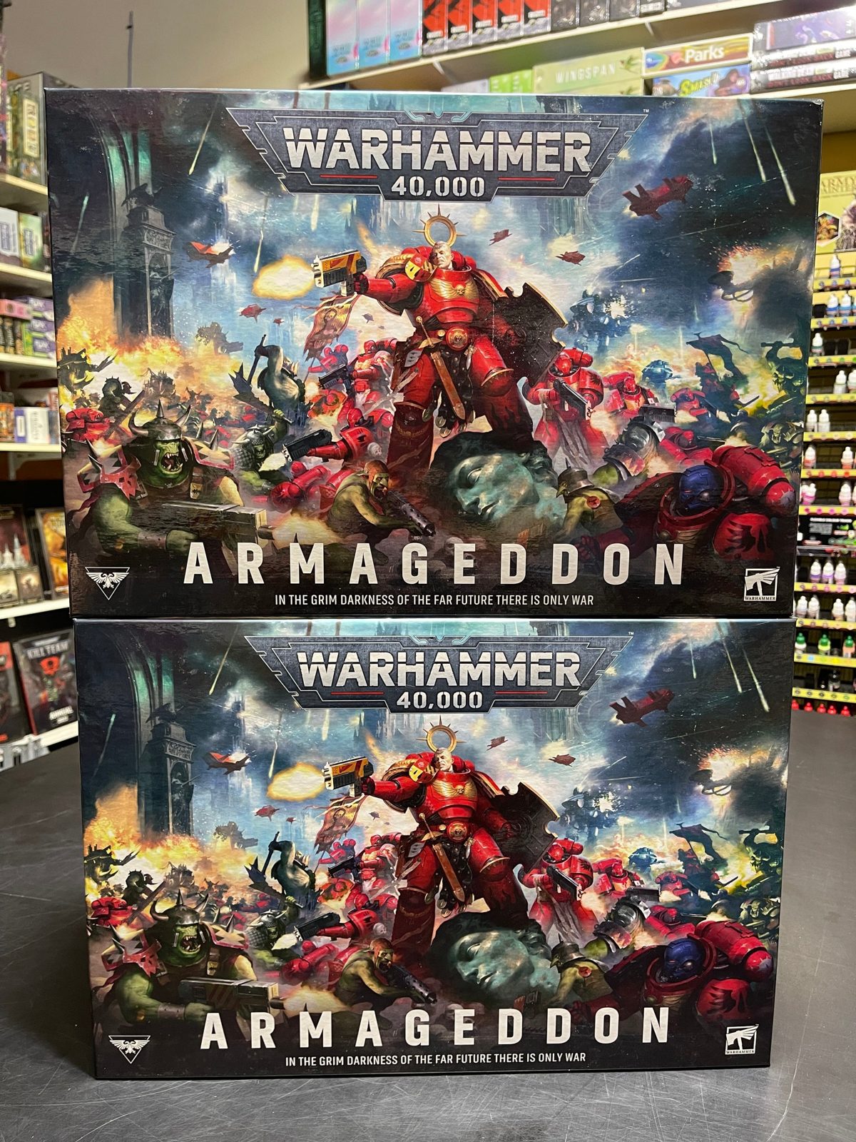 Two Warhammer 40,000 Armageddon boxes on the counter at Wiser's, with paint racks and games behind