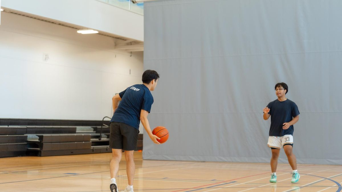 Two young people playing basketball in the gym at Timms Community Centre