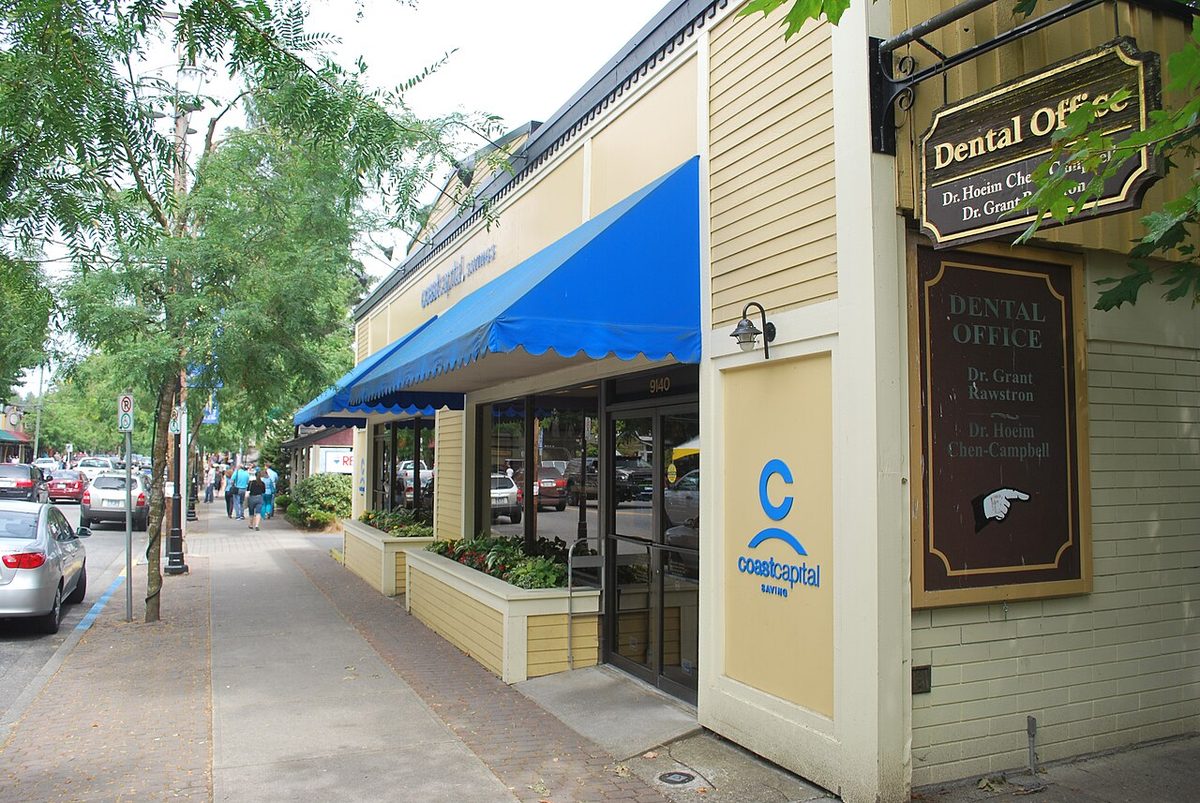 A heritage-style Glover Road building with a blue awning, tree-lined sidewalk in front