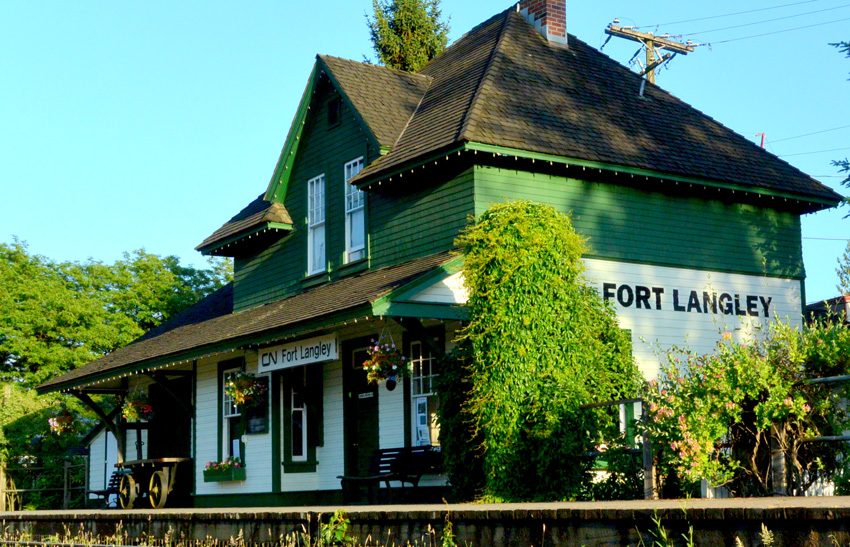 The green-and-white 1915 Fort Langley CN Station with hanging flower baskets on the platform