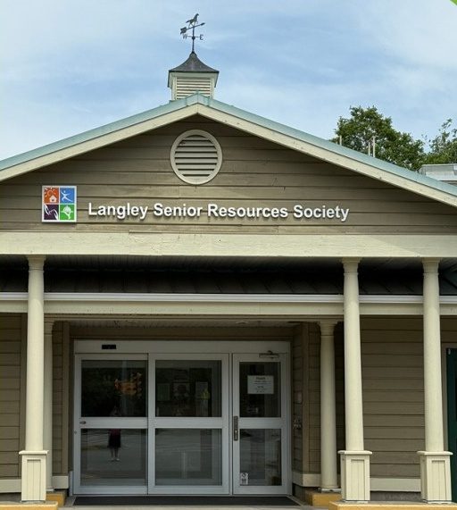 The front entrance of the Langley Senior Resources Society centre, a pale green building with white columns and a weathervane on the roof