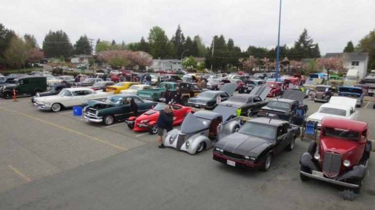 Rows of vintage and classic cars parked in the Aldergrove Community Secondary School lot, with trees behind