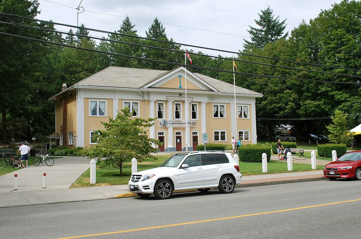 The cream-coloured Fort Langley Community Hall with columns and a lawn in front