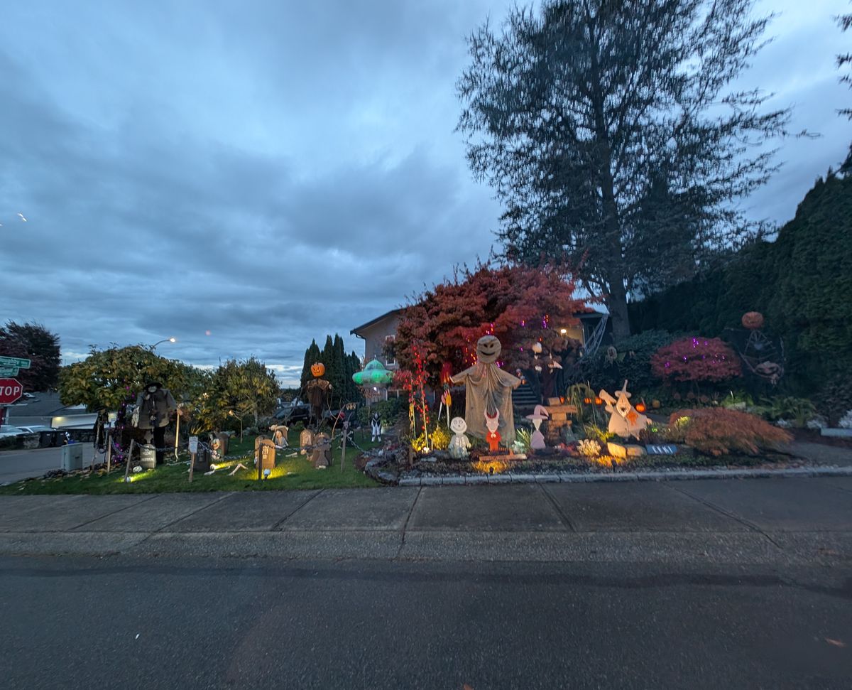 A corner lot on Wakefield Drive with a pumpkin-headed scarecrow, glowing headstones and a green flying saucer