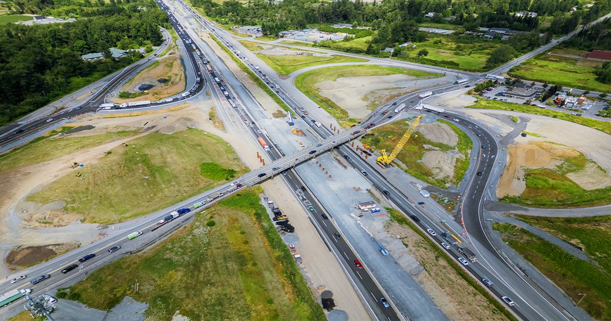 Aerial view of the 264 Street and Highway 1 interchange under construction, with the new bridge, cranes and traffic