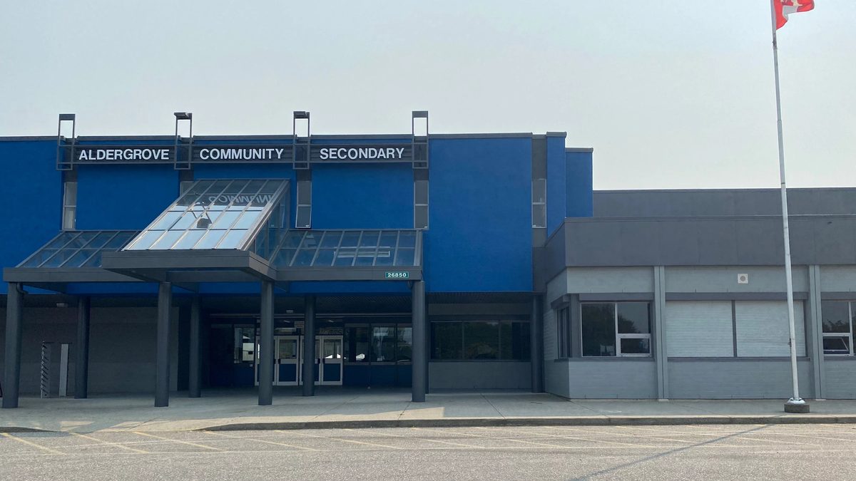The front of Aldergrove Community Secondary School, a blue-fronted building with a glass canopy over the entrance and a Canadian flag