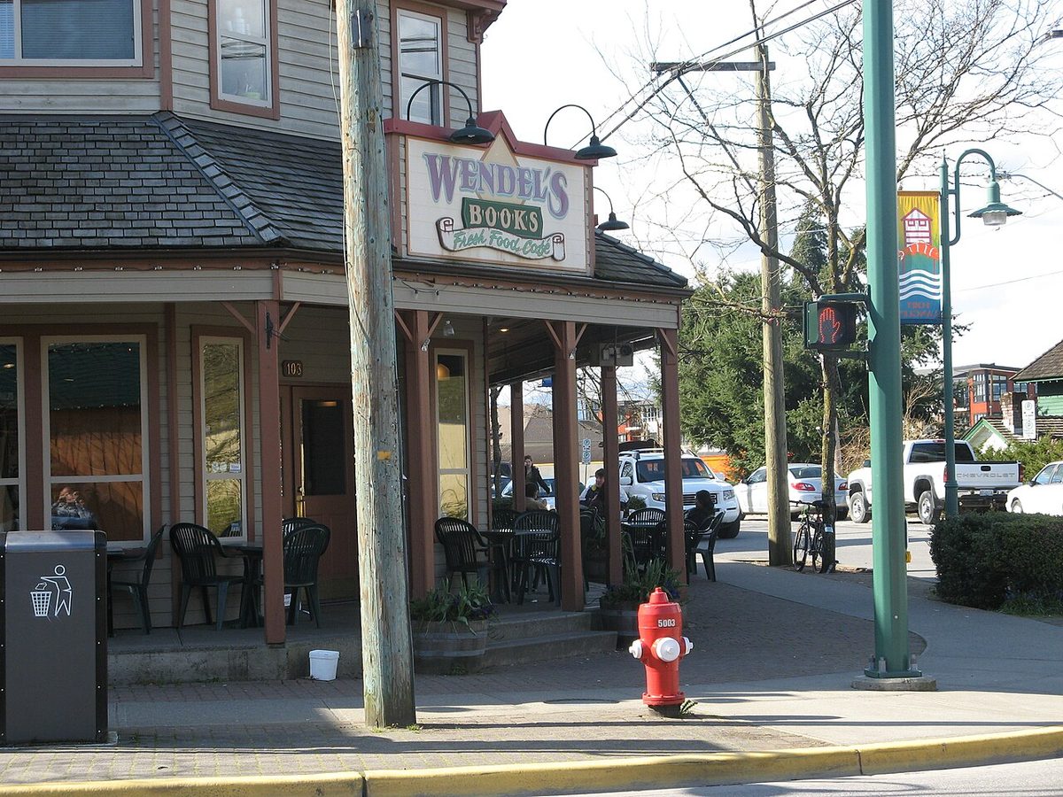 The covered corner entrance and sign of Wendel's bookstore and cafe at Glover Road and Mavis Avenue in Fort Langley, with a street banner beside it