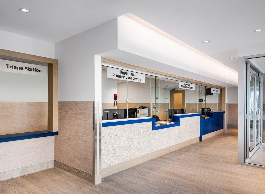 The triage station and reception counter inside the Langley Urgent and Primary Care Centre, with signs reading Triage Station and Urgent and Primary Care Centre