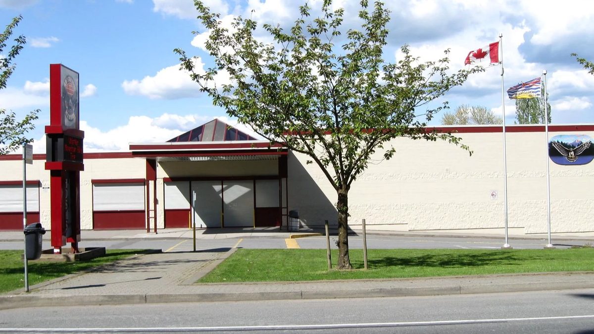 The front of H.D. Stafford Middle School in Langley City, with flagpoles, a tree and the red entrance sign
