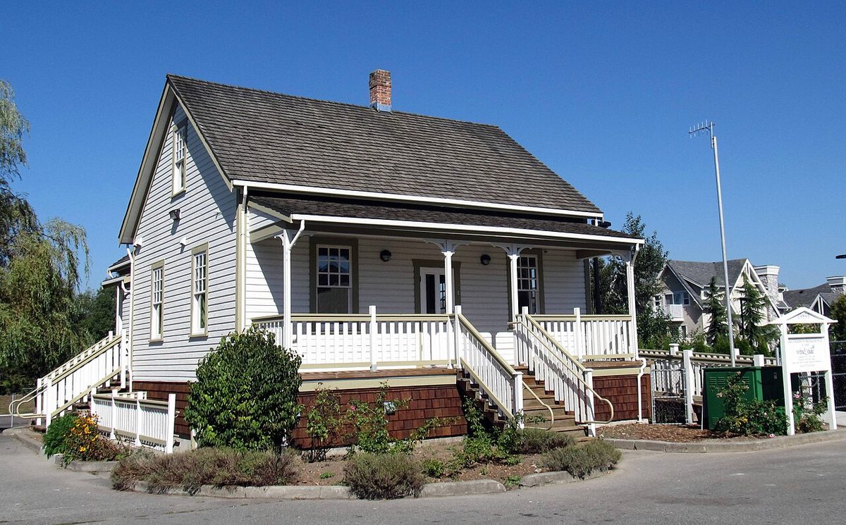 Matheson House, a white and grey two-storey heritage house with a covered front porch and shake roof, in Langley Meadows Park, Langley