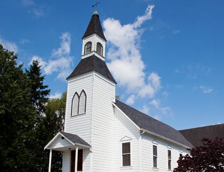 The white wooden Milner Chapel with its small steeple and arched windows, beside Milner Hall in Langley