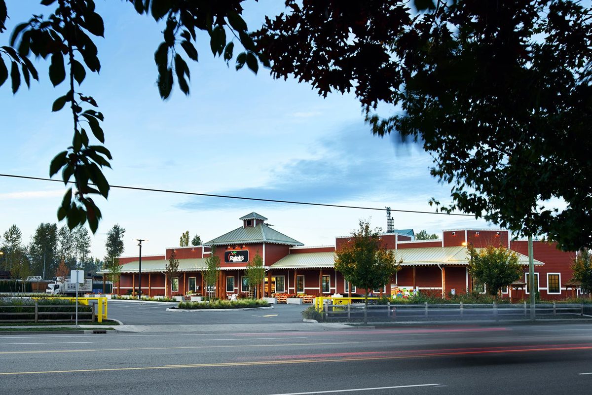 The red-roofed barn-style building of Ralph's Farm Market on Fraser Highway in Murrayville, seen across the road at dusk