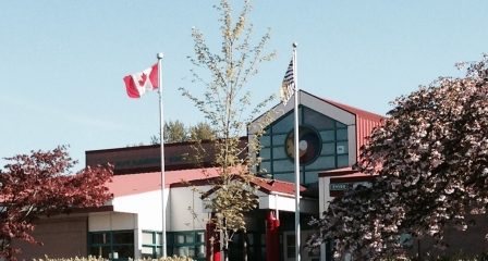 The front entrance of Alex Hope Elementary in Walnut Grove, with flagpoles and flowering trees beside the building