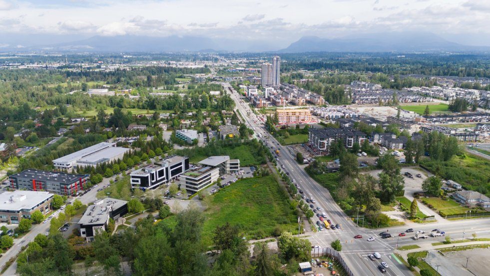 Aerial view along 200 Street in Willoughby, with new apartment buildings, townhouses and office buildings beside a busy road