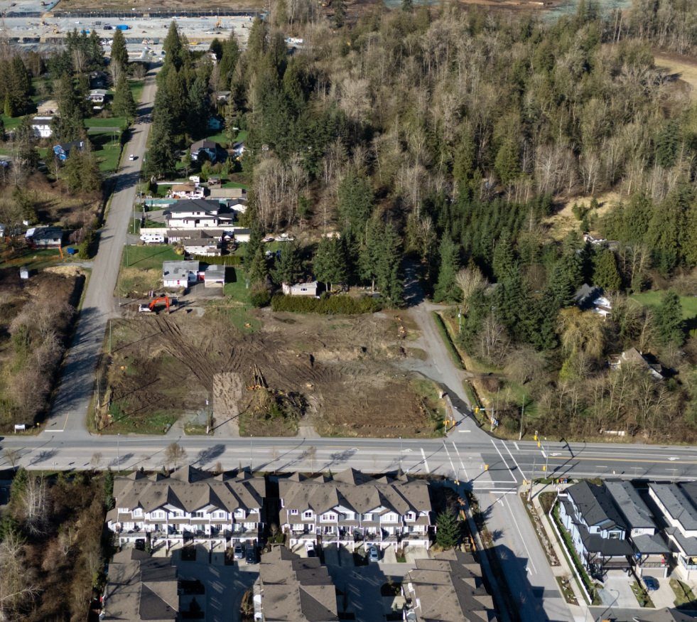 Aerial view of the Smith area of Willoughby, with new townhouse rows along a road at the bottom and older homes, cleared lots and tall trees above