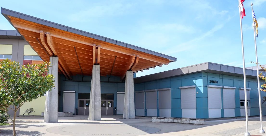Main entrance of Yorkson Creek Middle School, with a timber-and-concrete canopy over double doors and a teal-panelled wing to the right