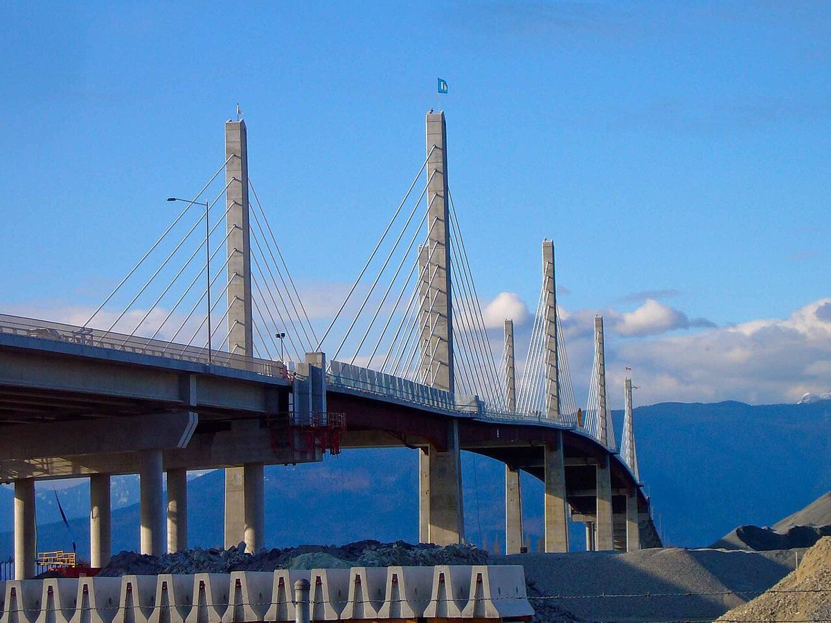 The cable-stayed towers of the Golden Ears Bridge against a blue sky and mountains