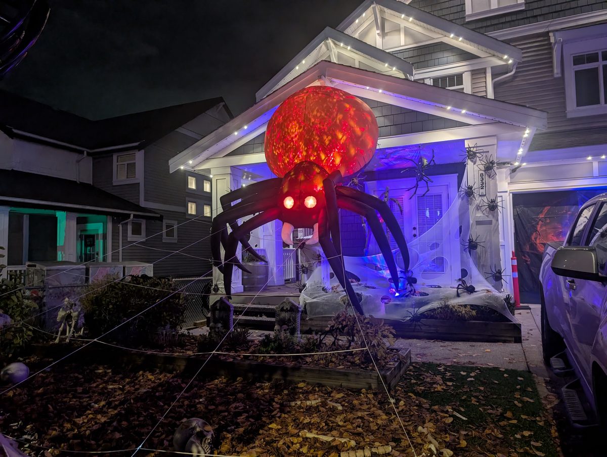 A giant red spider climbing the front of a house